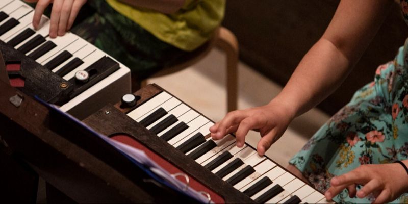 Två barn spelar på varsitt piano
