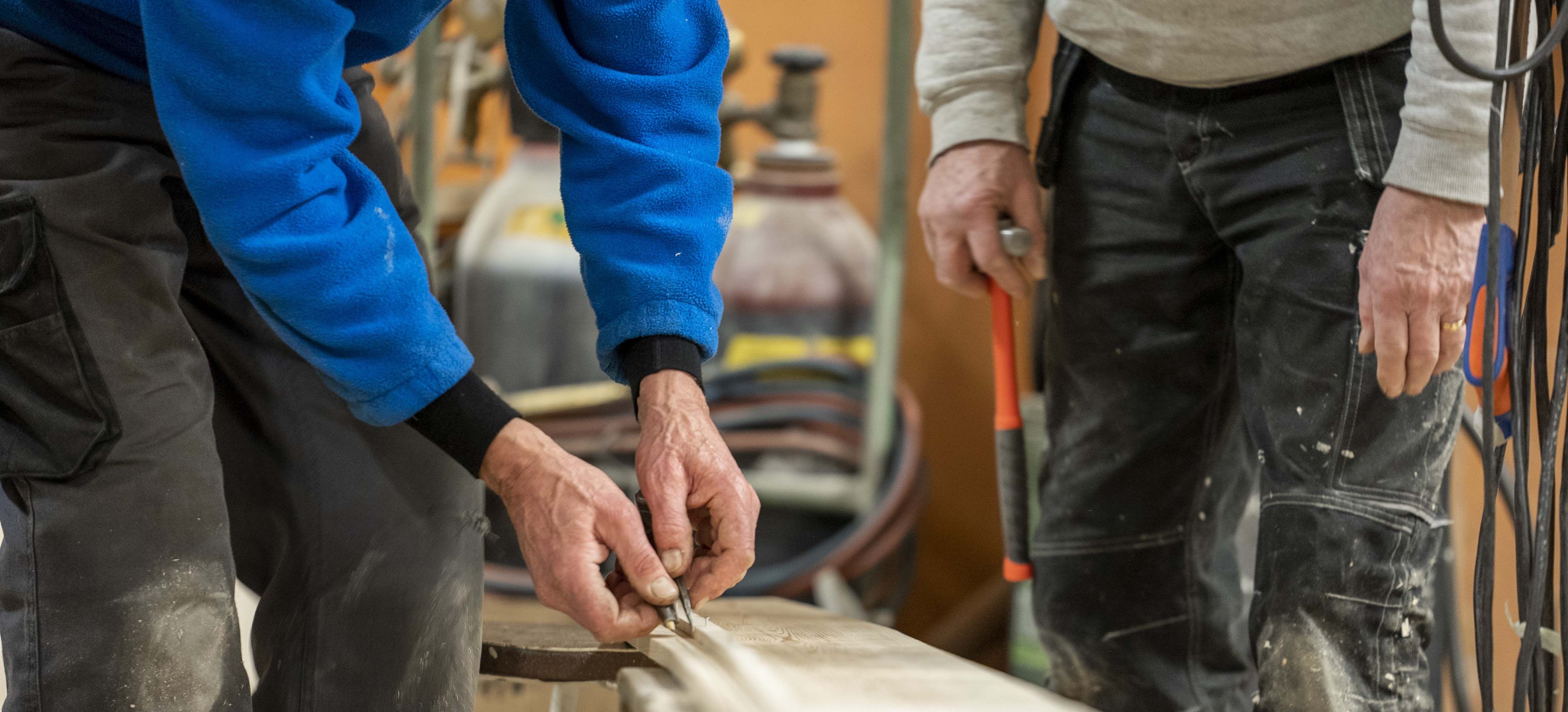 Klinkbåtsbygge i Bosund, Larsmo. Fotot visar hur borden passas in, vi ser enbart händer som håller ett verktyg och jobbar med bordet. Foto: Prime Productions