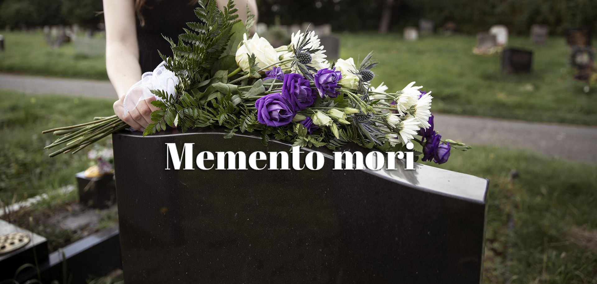 En gravsten prydd med blommor och texten Memento mori ligger i mitten av gravstenen